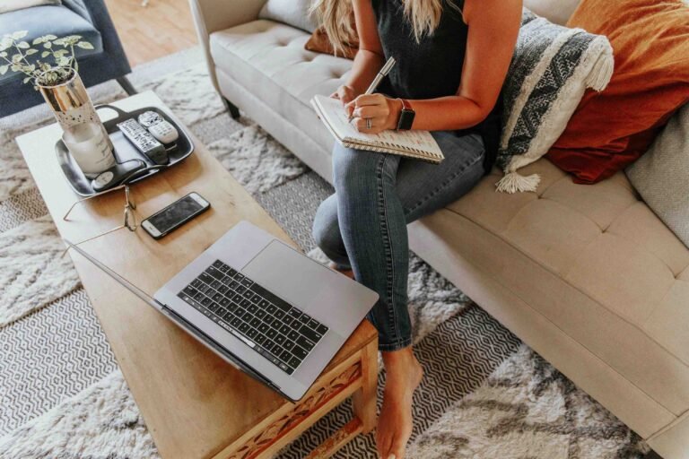 Image décorative représentant une femme écrivant sur un carnet, avec un ordinateur posé devant elle.